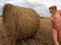 Naked exhibitionist girl in a field with straw